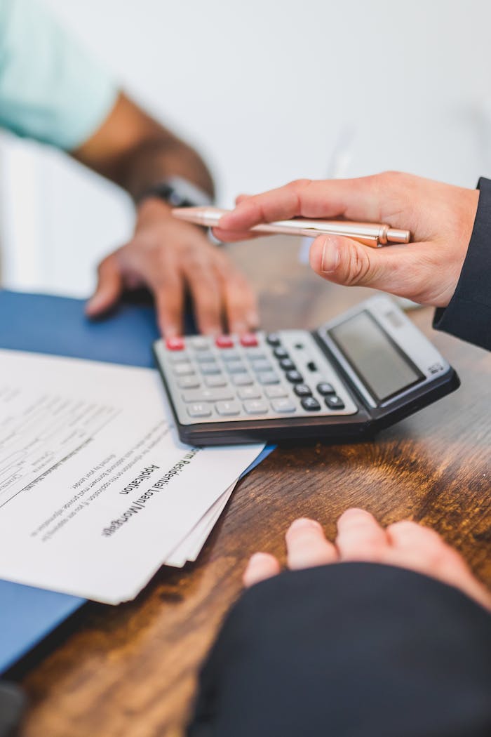 Hands working with a calculator and documents at a business meeting.